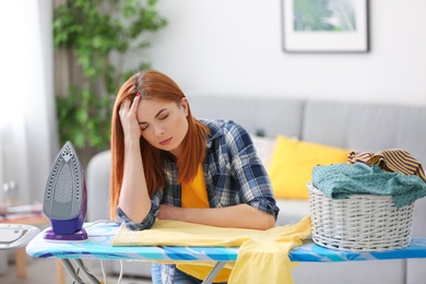 Photo of Tired housewife ironing clothes at home