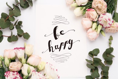 Photo of Frame of beautiful flowers and paper card with handwritten text Be happy on white background, flat lay