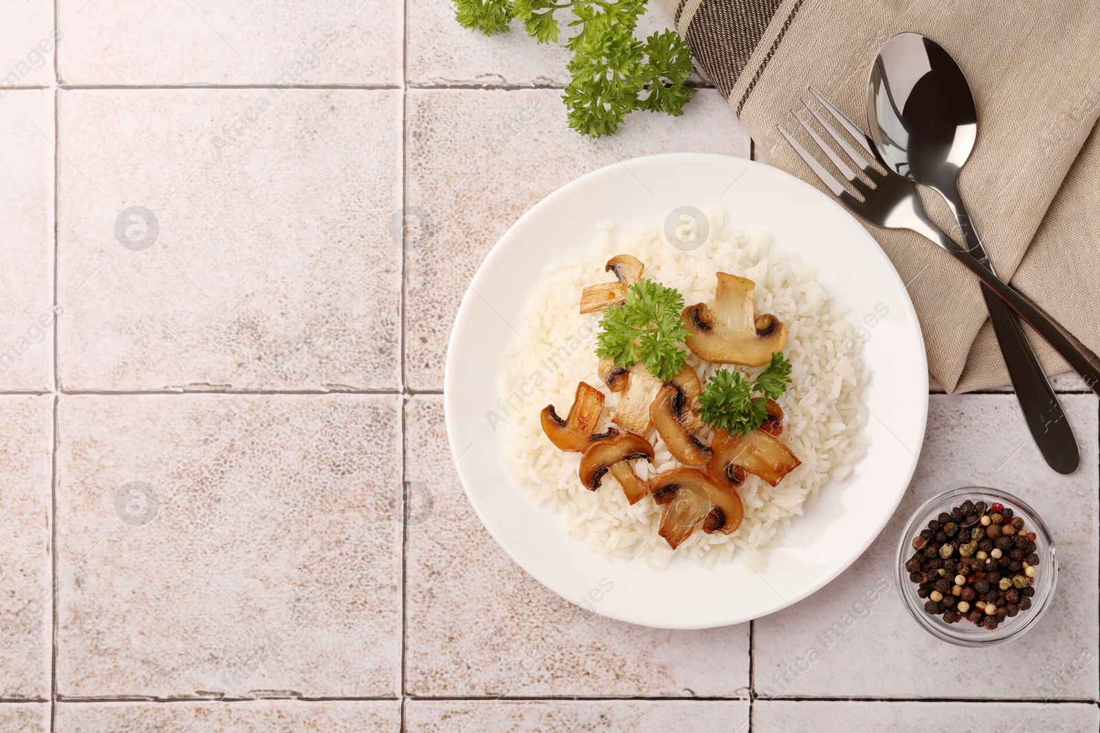 Photo of Delicious rice with parsley and mushrooms served on tiled table, flat lay. Space for text