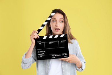 Photo of Making movie. Beautiful surprised woman with clapperboard on yellow background