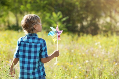 Cute little boy with pinwheel outdoors, space for text. Child spending time in nature