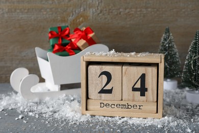 Photo of December 24 - Christmas Eve. Wooden block calendar and decor on grey table
