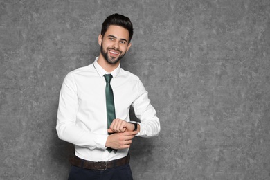 Portrait of confident businessman with wristwatch on grey background. Space for text