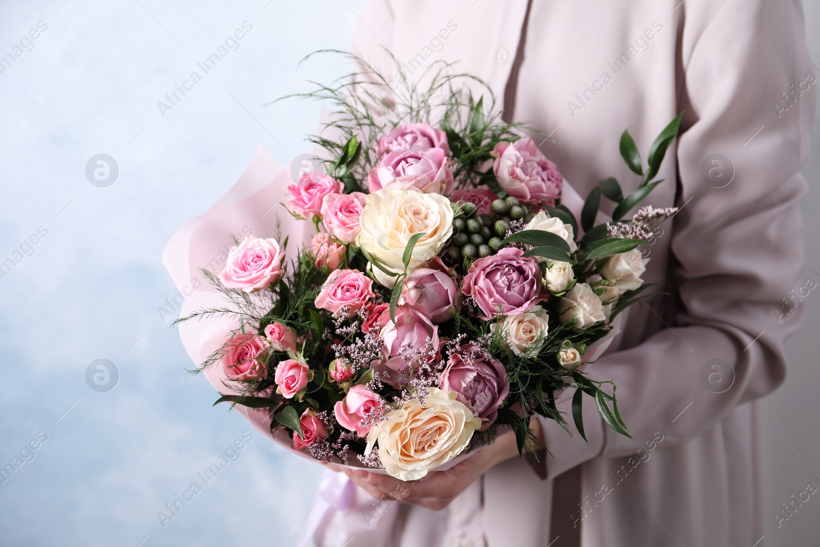 Photo of Woman with bouquet of beautiful roses on light blue background, closeup