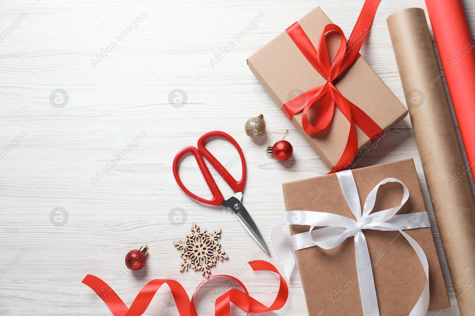 Photo of Flat lay composition with beautiful Christmas gift boxes and wrapping paper on white wooden table. Space for text