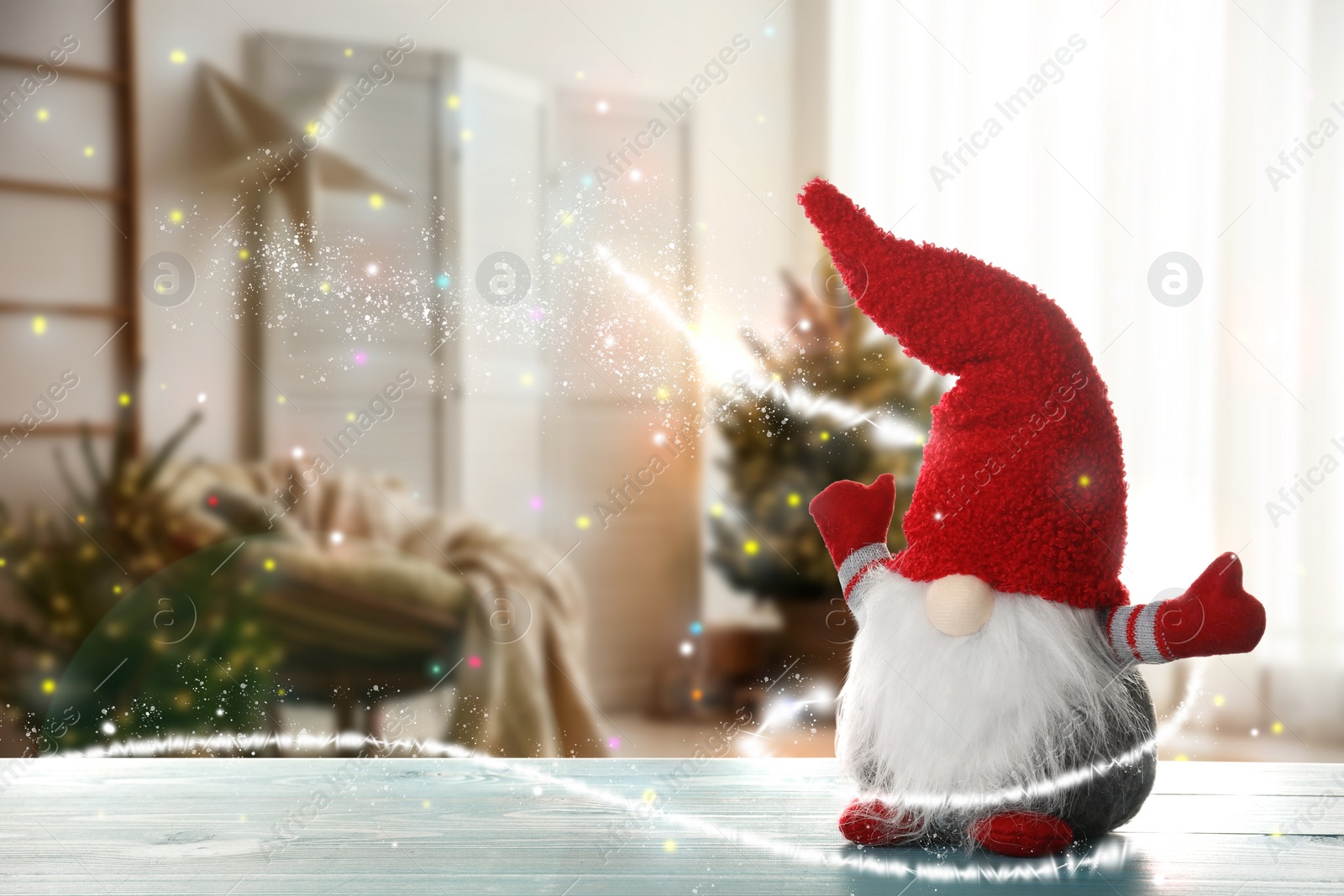 Image of Funny Christmas gnome on turquoise wooden table in room with festive decorations. Space for text