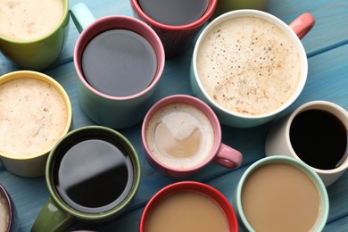 Photo of Many cups of different coffee drinks on light blue wooden table, above view