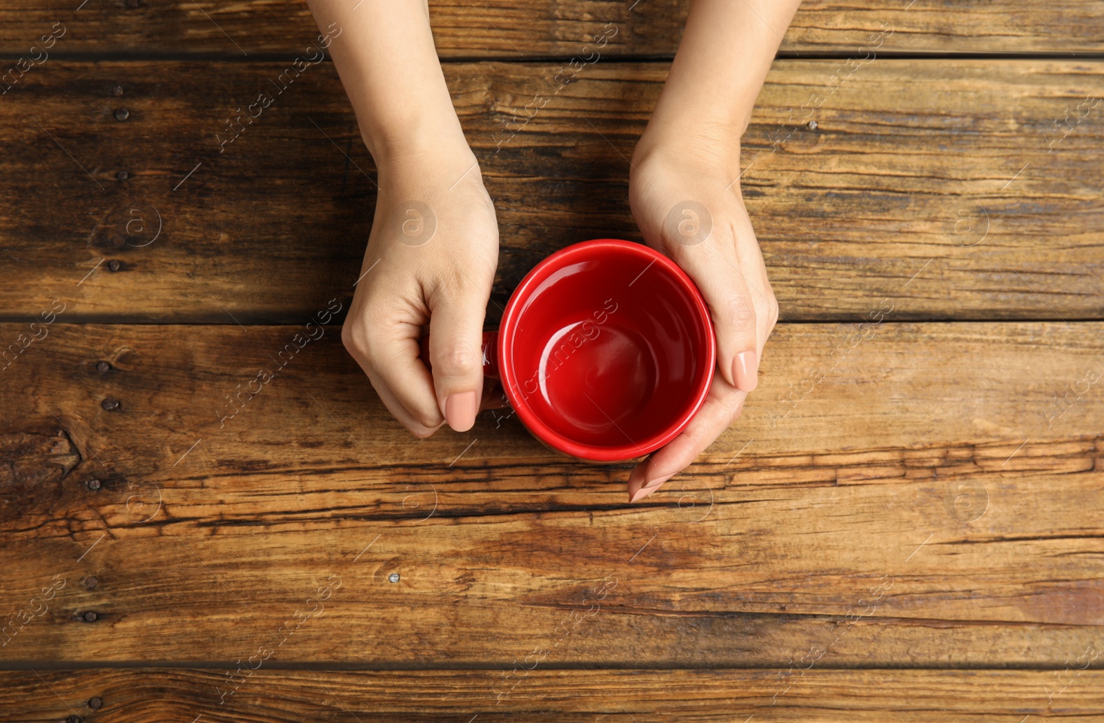 Photo of Woman with empty cup at wooden table, top view