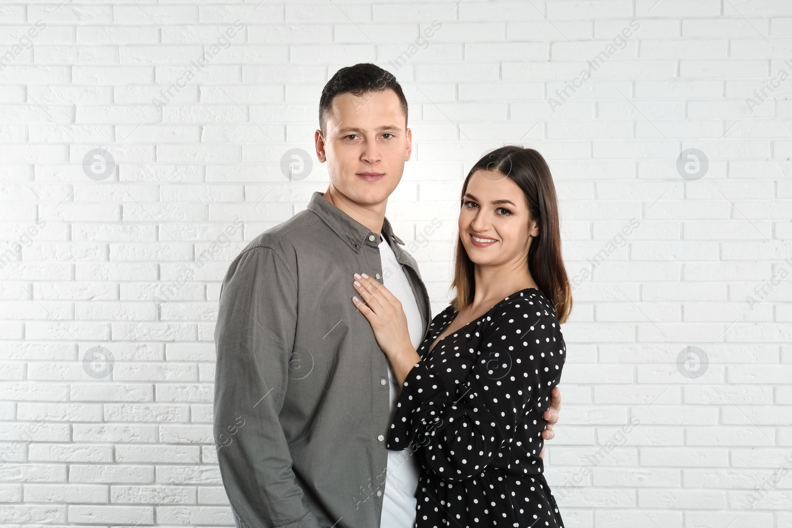 Photo of Happy young couple near white brick wall