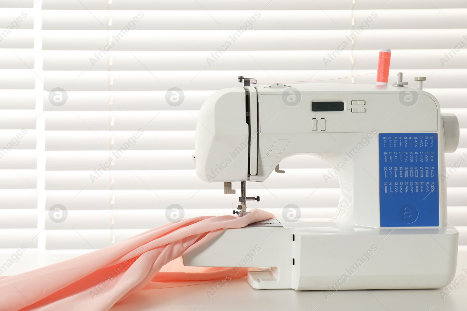 Photo of White sewing machine and fabric on light table indoors