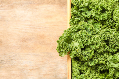 Photo of Fresh kale leaves on wooden table, closeup. Space for text