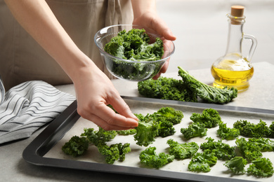 Woman preparing kale chips at table, closeup