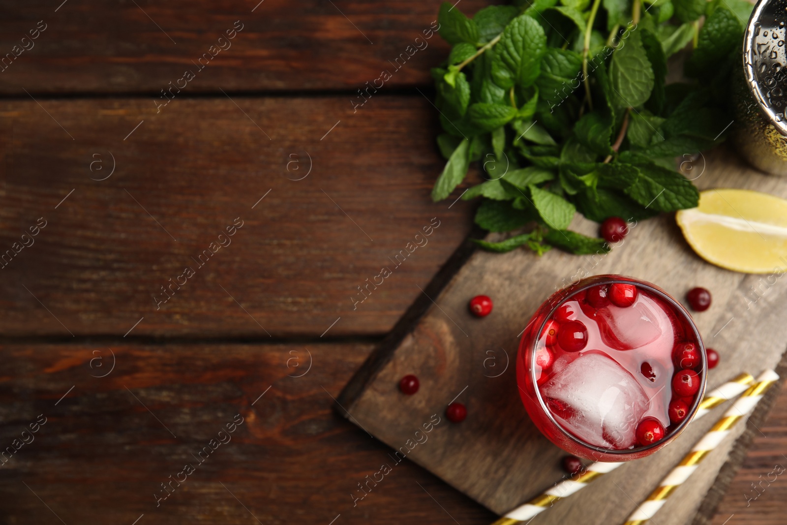 Photo of Tasty refreshing cranberry cocktail and fresh ingredients on wooden table, flat lay. Space for text