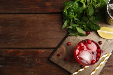 Photo of Tasty refreshing cranberry cocktail and fresh ingredients on wooden table, flat lay. Space for text