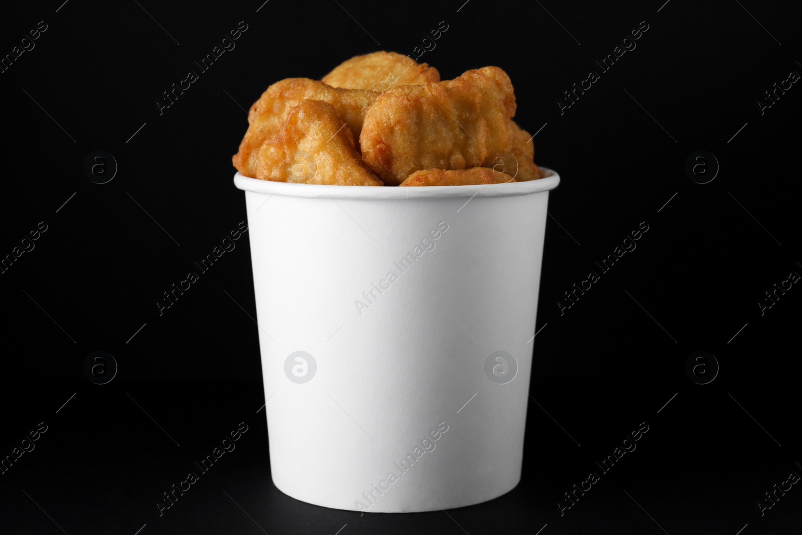 Photo of Bucket with delicious chicken nuggets on black background