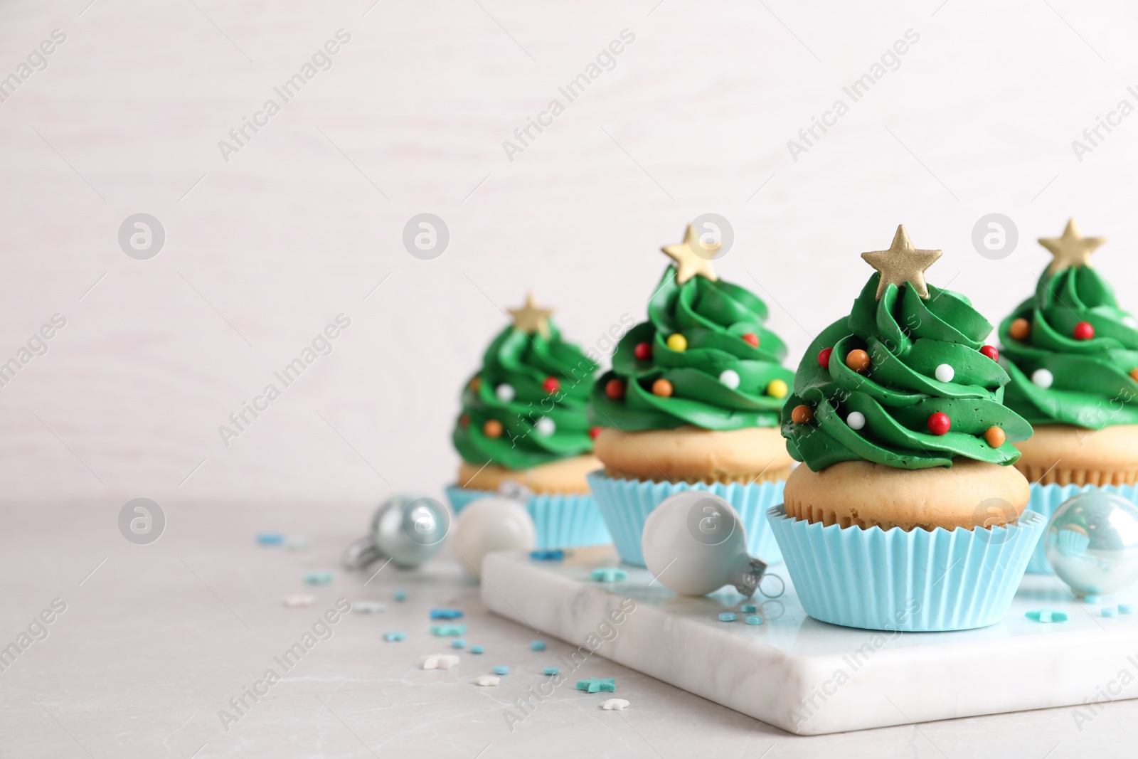 Photo of Christmas tree shaped cupcakes and decor on table. Space for text