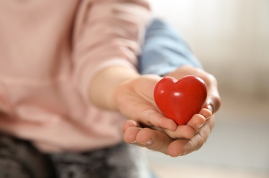 Man and his daughter holding red heart on blurred background, closeup. Children's doctor