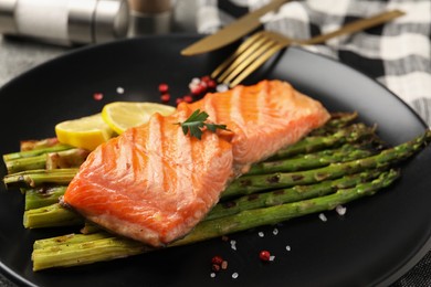 Photo of Tasty grilled salmon with asparagus and spices served on table, closeup