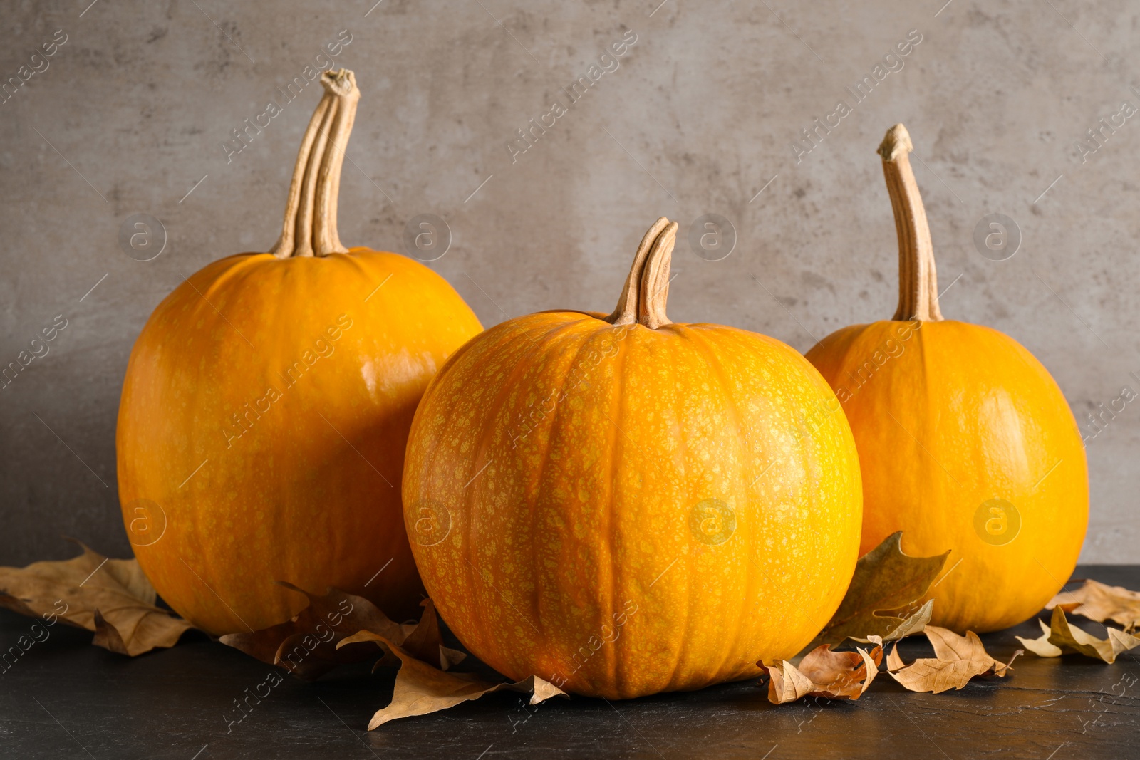 Photo of Ripe pumpkins and autumn leaves on black table