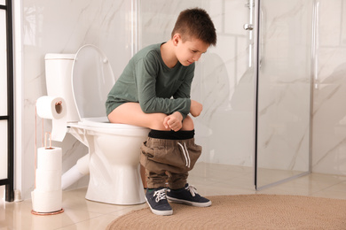 Boy suffering from hemorrhoid on toilet bowl in rest room