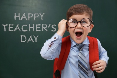 Image of Emotional little child wearing glasses near chalkboard with text Happy Teacher's Day