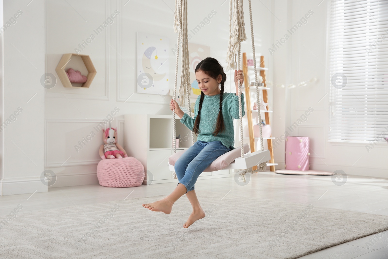 Photo of Cute little girl playing on swing at home