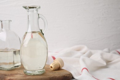 Photo of Vinegar in glass jug and bottle on table, space for text