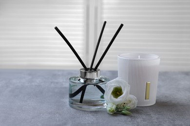 Photo of Reed diffuser, scented candle and eustoma flowers on gray marble table