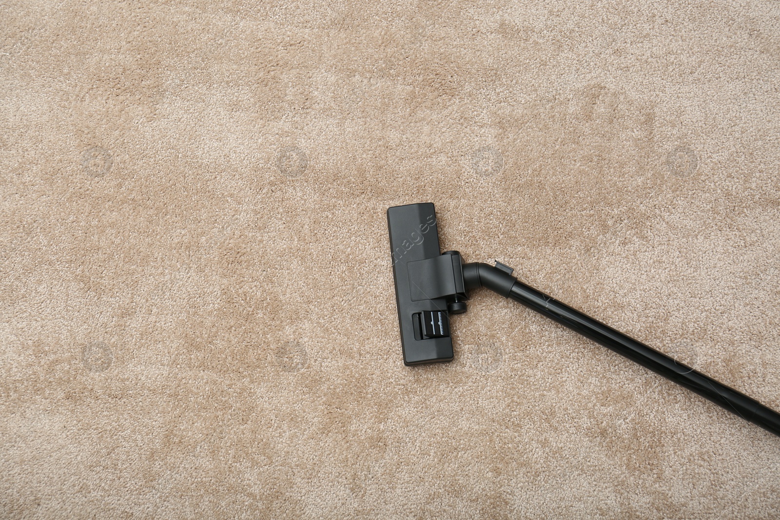 Photo of Removing dirt from carpet with modern vacuum cleaner indoors, top view. Space for text