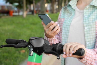 Woman using smartphone to pay and unblock electric kick scooter outdoors, closeup