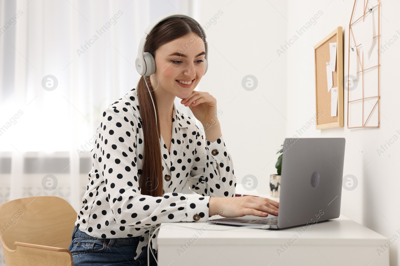 Photo of E-learning. Young woman using laptop during online lesson at table indoors