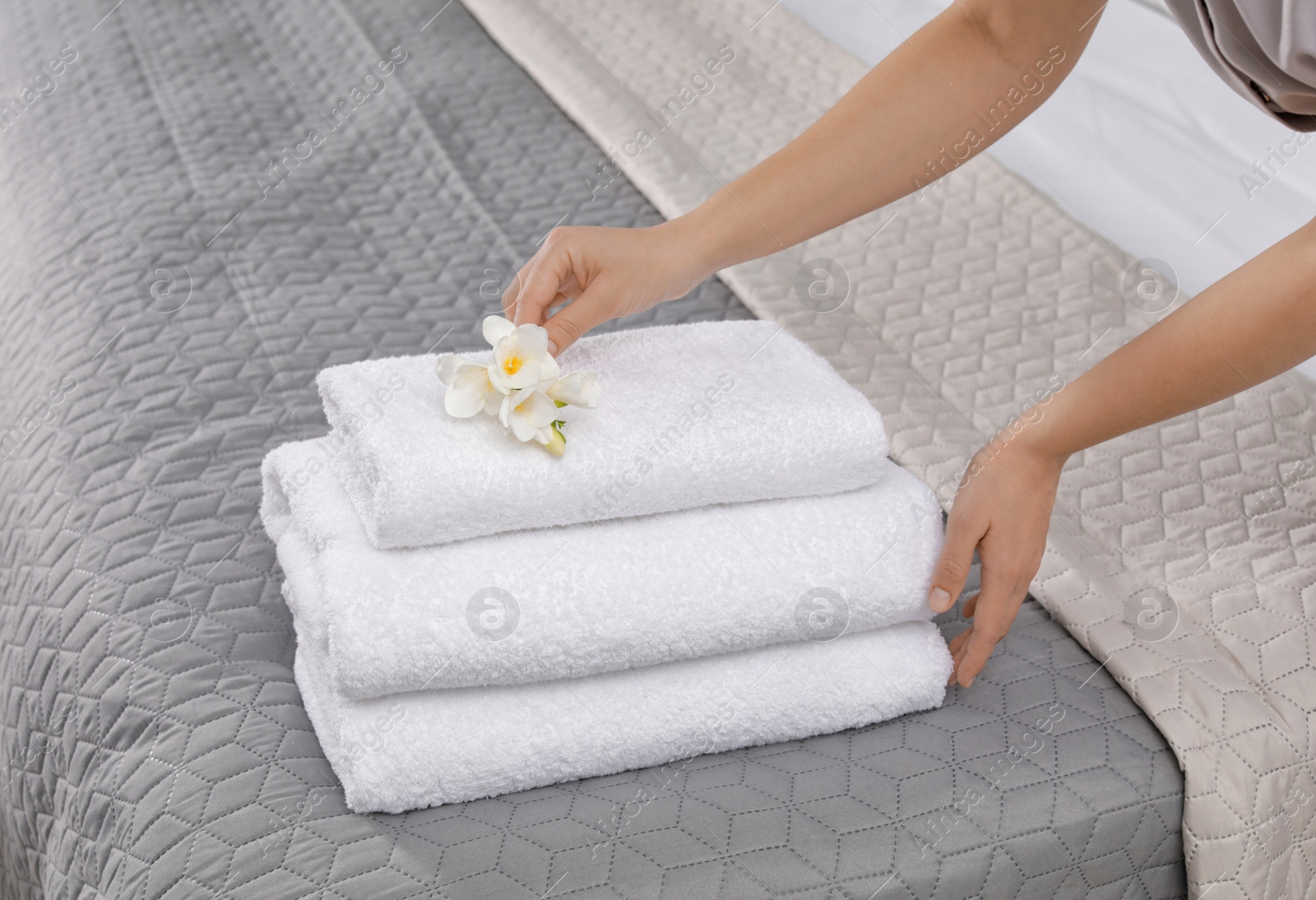 Photo of Maid putting flowers on fresh towels in hotel room, closeup