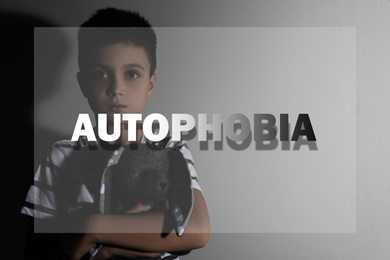 Image of Sad little boy with toy near light wall. Autophobia - fear of isolation