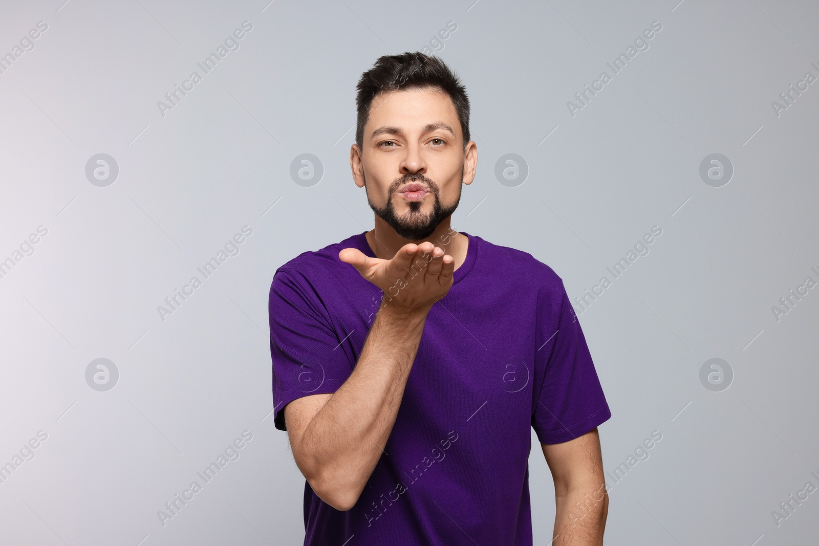 Photo of Handsome man blowing kiss on light grey background