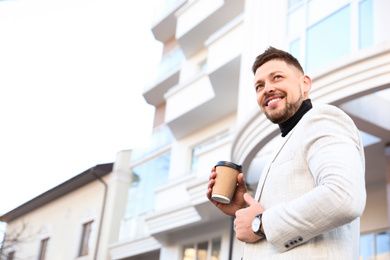 Photo of Businessman with cup of coffee on city street in morning