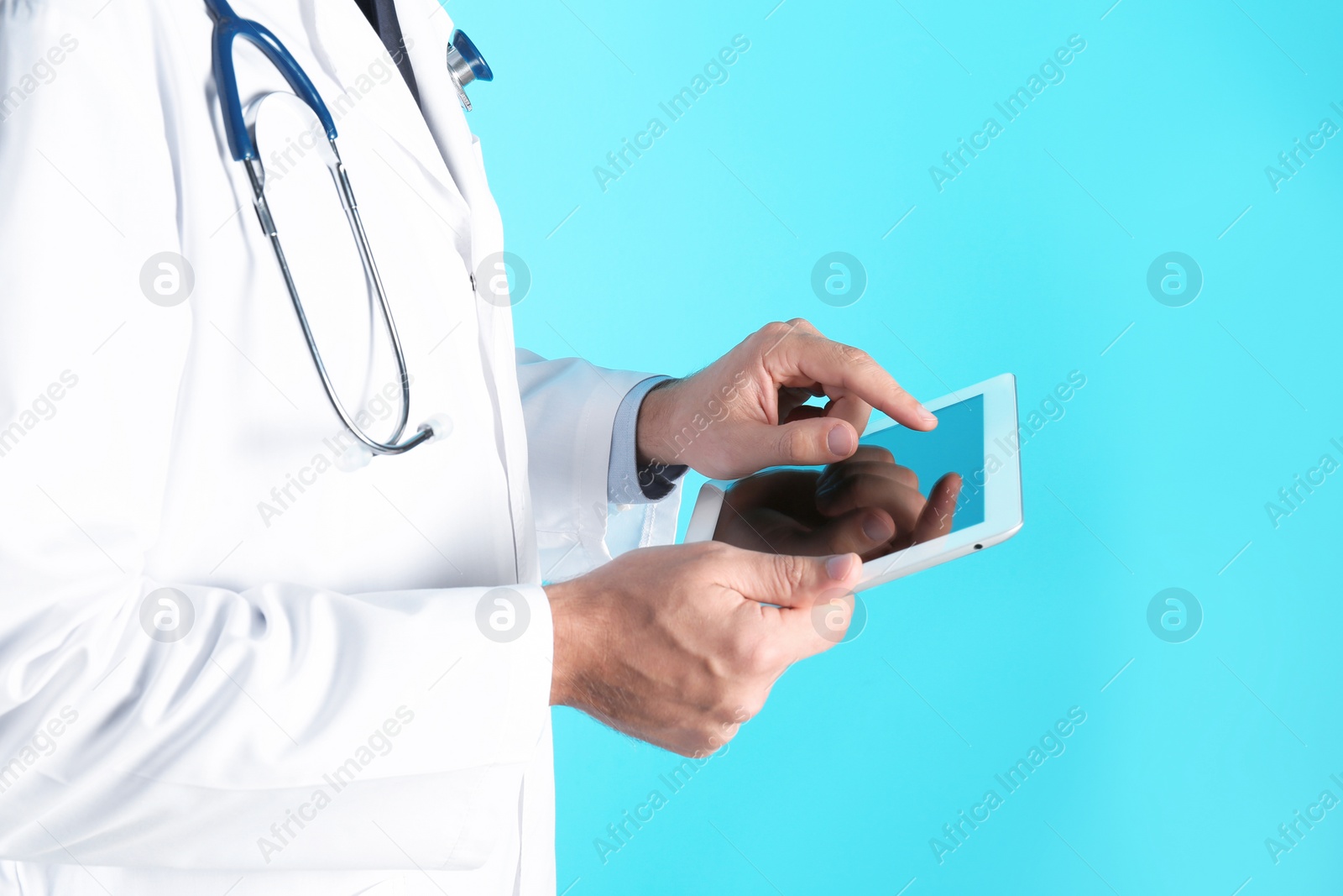 Photo of Male doctor holding modern tablet on color background, closeup