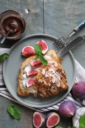 Photo of Delicious croissant with figs and cream served on light blue wooden table, flat lay