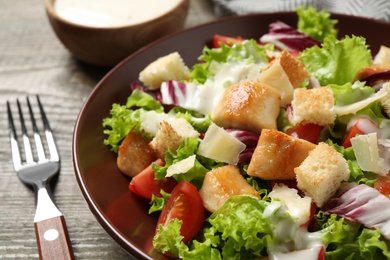 Photo of Delicious fresh Caesar salad on wooden table, closeup