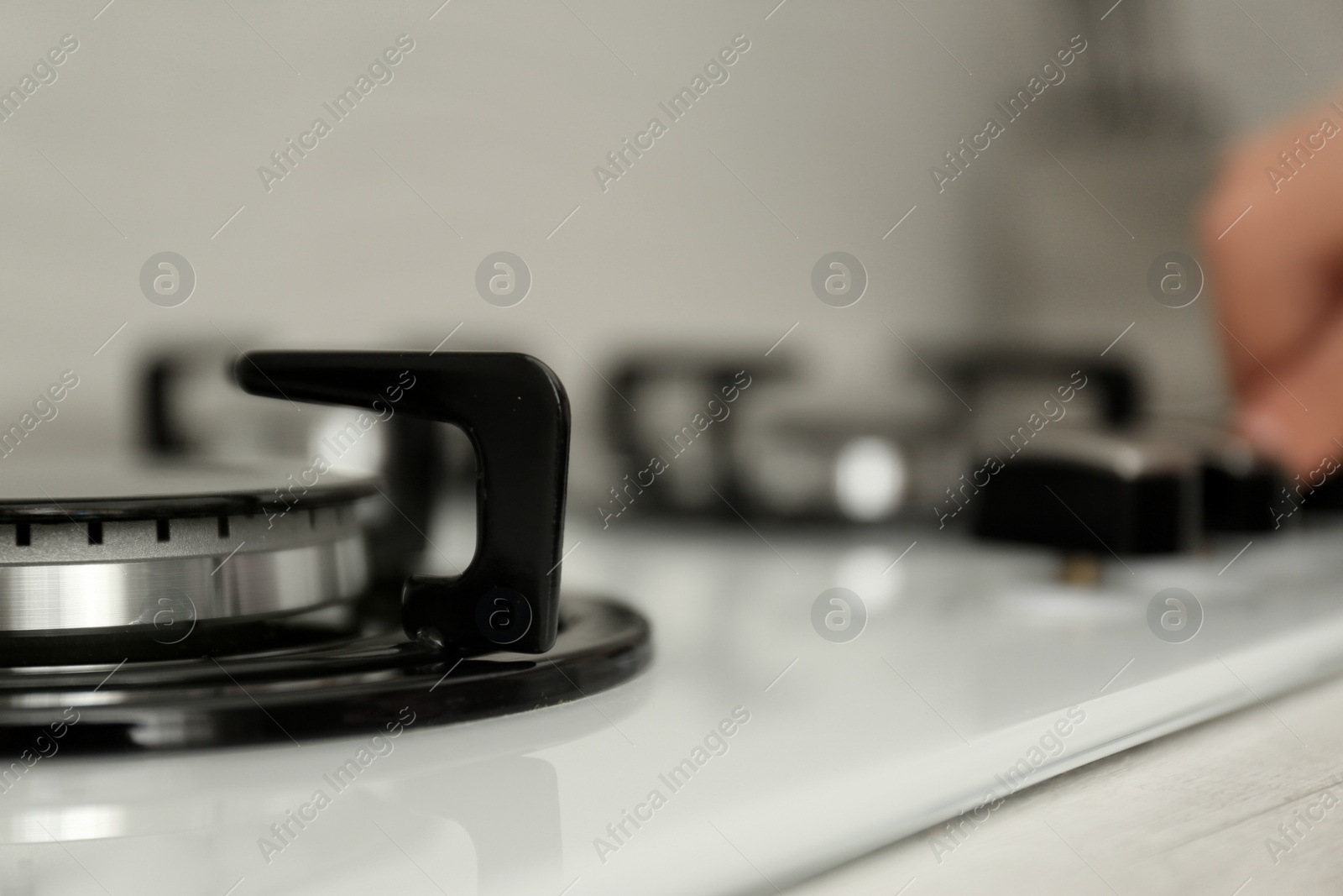 Photo of Woman regulating cooking mode on gas stove panel, closeup