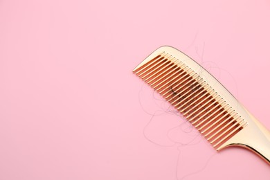 Photo of Comb with lost hair on pink background, space for text