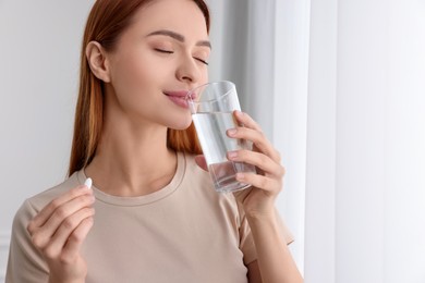 Photo of Beautiful young woman with vitamin pill and glass of water
