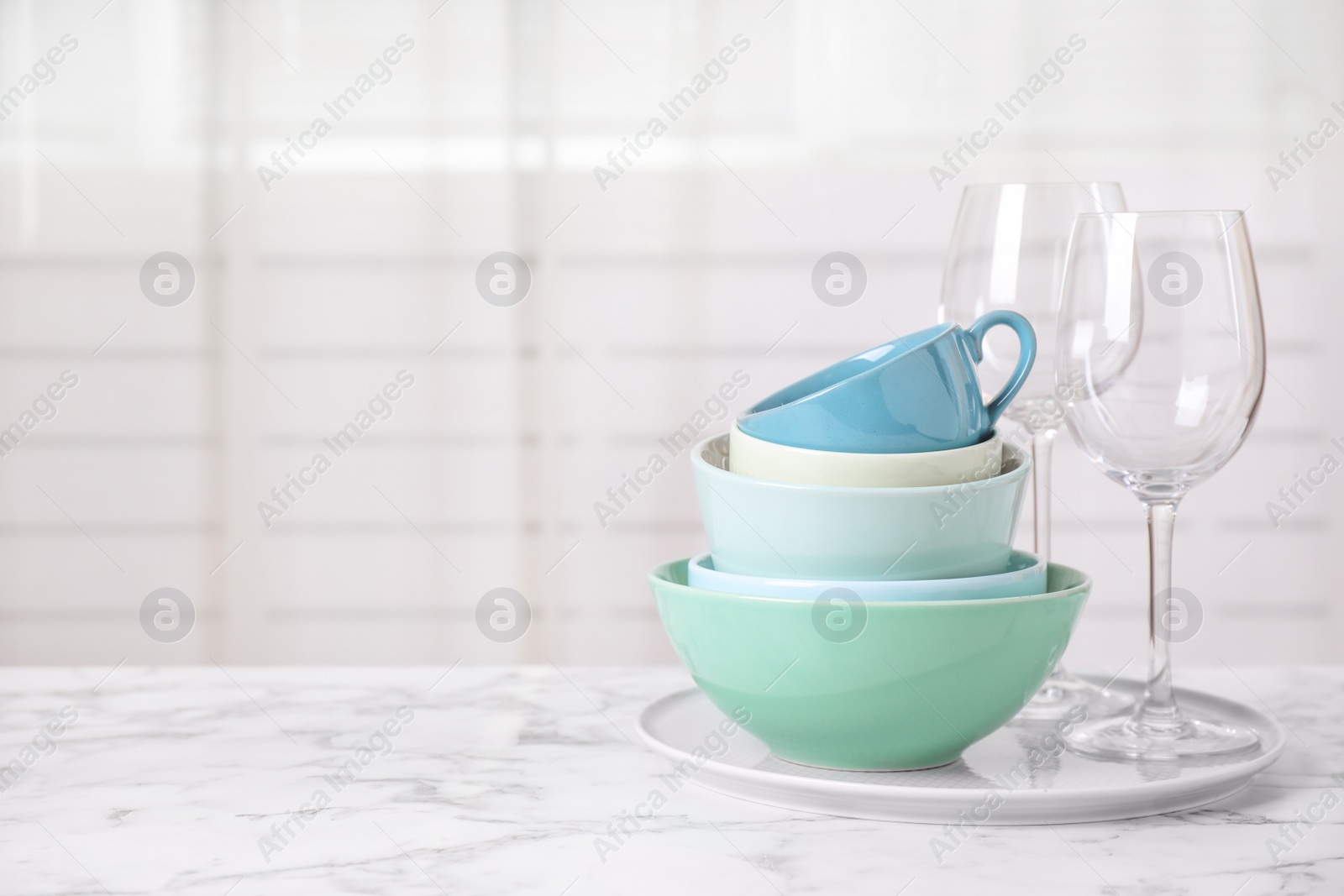 Photo of Set of clean tableware on white marble table. Space for text