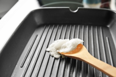 Wooden spoon with coconut oil in frying pan, closeup. Healthy cooking