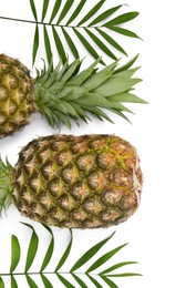 Photo of Whole ripe pineapples and green leaves on white background, flat lay. Space for text