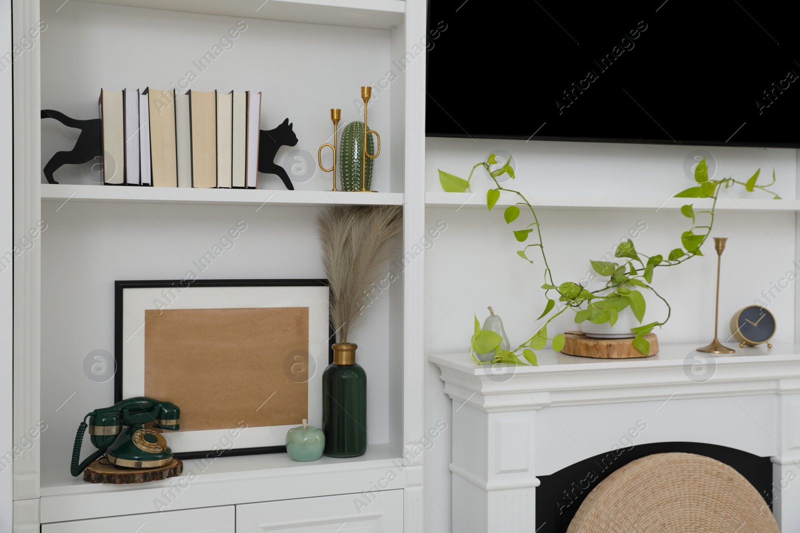 Photo of Stylish shelves with different decor elements and TV set in room. Interior design