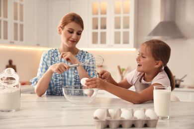 Photo of Mother and daughter making dough together in kitchen