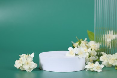 Presentation of product. White podium and beautiful jasmine flowers on green background, space for text