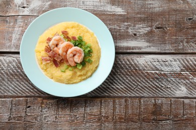 Plate with fresh tasty shrimps, bacon, grits and green onion on wooden table, top view. Space for text