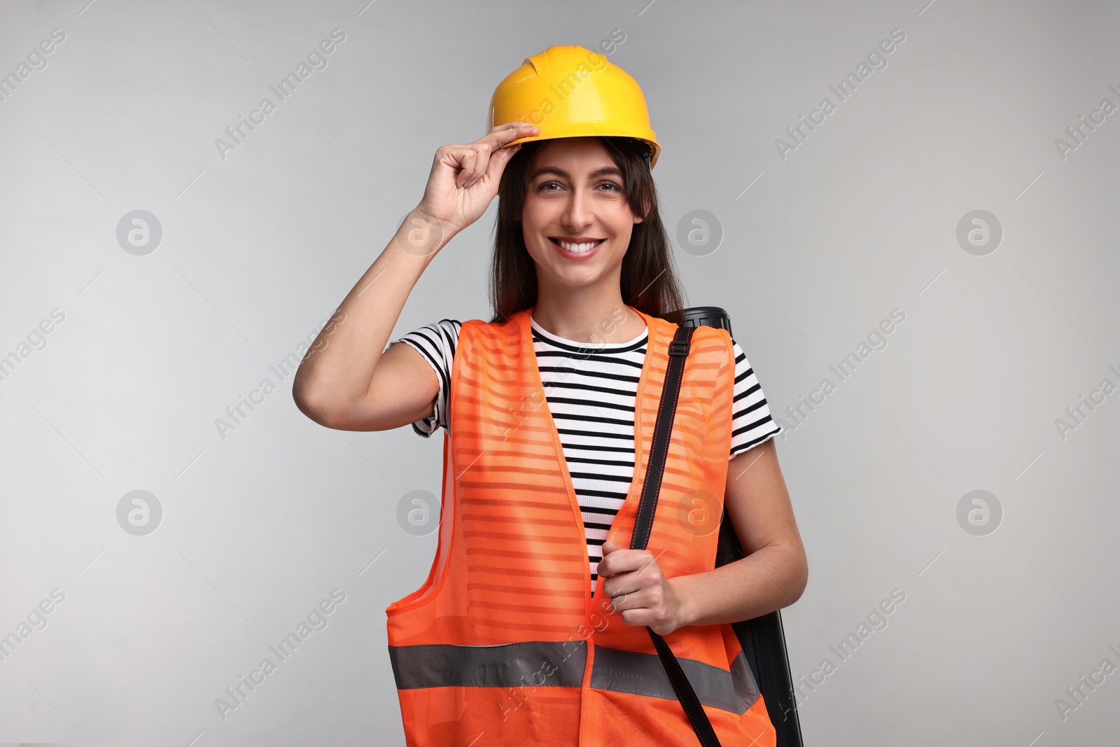 Photo of Architect in hard hat with tube on light grey background