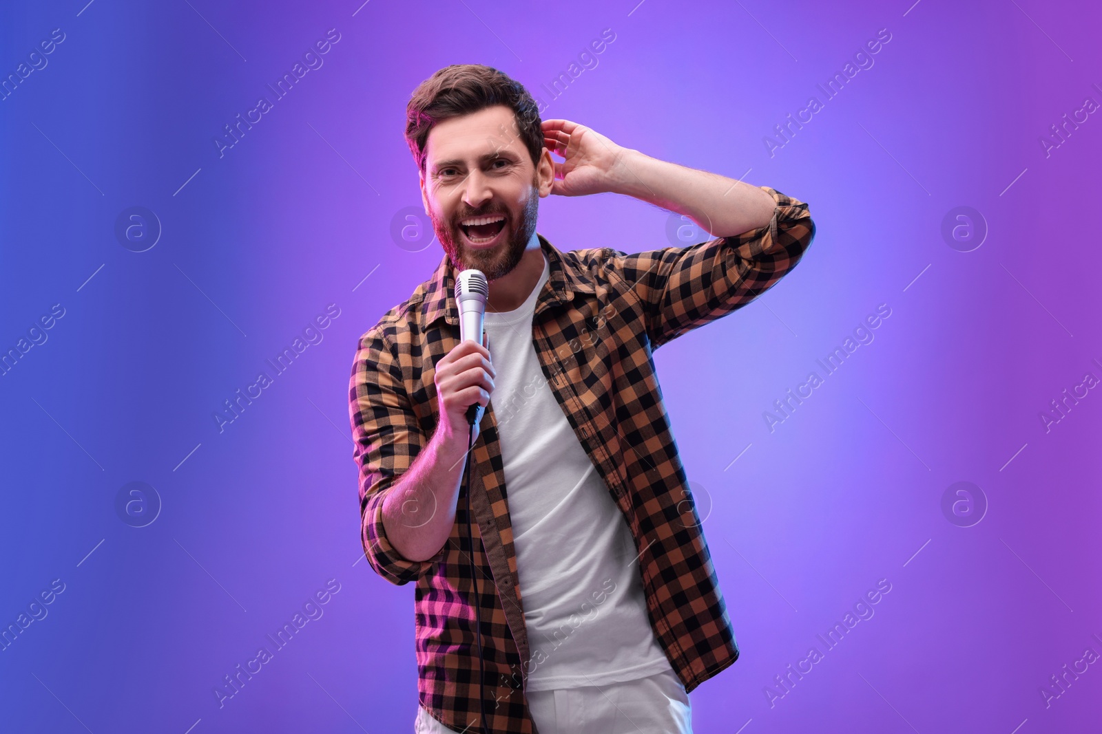 Photo of Handsome man with microphone singing in neon lights